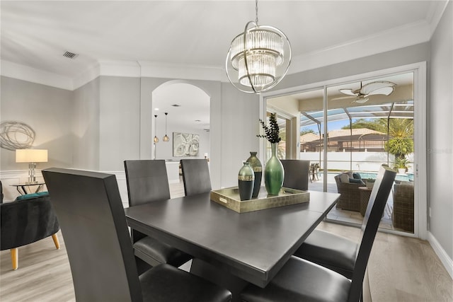 6426 Montclair Bluff Ln, Windermere, FL 34786 - dining space with light wood finished floors, arched walkways, ornamental molding, a ceiling fan, and a chandelier