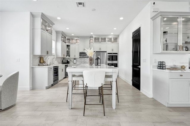 5609 Zestar Ln, Loxahatchee, FL 33470 - kitchen with appliances with stainless steel finishes, beverage cooler, light countertops, a kitchen island, and recessed lighting