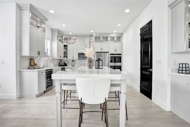 5609 Zestar Ln, Loxahatchee, FL 33470 - kitchen featuring appliances with stainless steel finishes, light wood-style flooring, wine cooler, a kitchen island, and recessed lighting