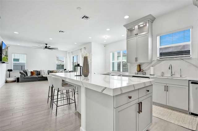 5609 Zestar Ln, Loxahatchee, FL 33470 - kitchen featuring a sink, light stone countertops, recessed lighting, light wood-type flooring, and a center island