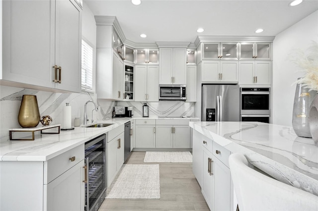 5609 Zestar Ln, Loxahatchee, FL 33470 - kitchen with appliances with stainless steel finishes, a sink, wine cooler, light stone counters, and recessed lighting