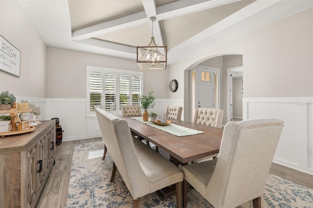1113 Fieldstone Cir, Oviedo, FL 32765 - dining space featuring arched walkways, wainscoting, a chandelier, light wood-style floors, and beam ceiling
