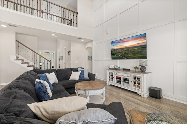 1113 Fieldstone Cir, Oviedo, FL 32765 - living room with a decorative wall, light wood-style floors, stairway, arched walkways, and a towering ceiling