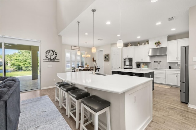 1113 Fieldstone Cir, Oviedo, FL 32765 - kitchen featuring a center island with sink, appliances with stainless steel finishes, under cabinet range hood, light countertops, and light wood-style floors