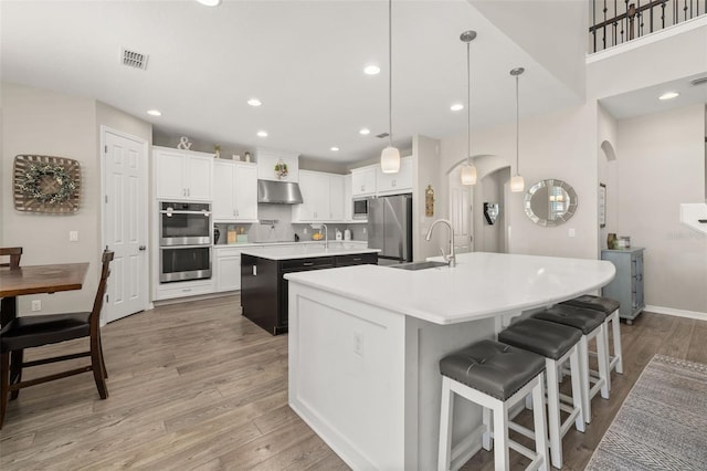 1113 Fieldstone Cir, Oviedo, FL 32765 - kitchen with a large island, arched walkways, appliances with stainless steel finishes, under cabinet range hood, and light countertops