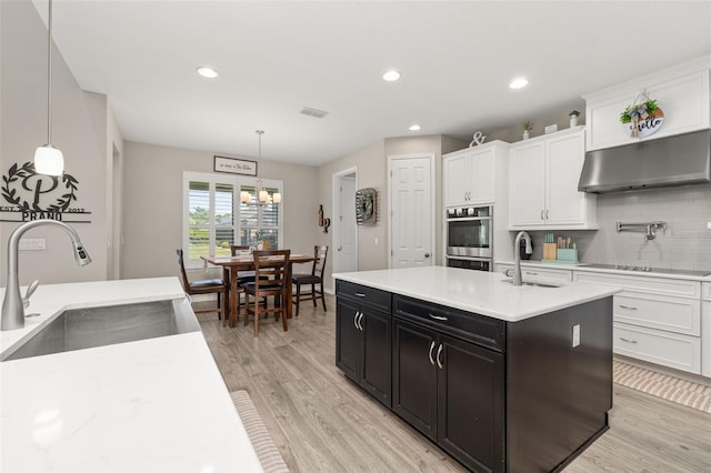 1113 Fieldstone Cir, Oviedo, FL 32765 - kitchen featuring under cabinet range hood, double oven, white cabinetry, decorative backsplash, and dark cabinets