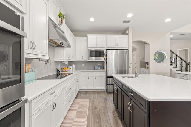 1113 Fieldstone Cir, Oviedo, FL 32765 - kitchen with appliances with stainless steel finishes, under cabinet range hood, white cabinets, light wood finished floors, and decorative backsplash