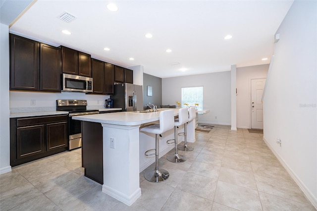 110 Claire Ln, Davenport, FL 33837 - kitchen with stainless steel appliances, an island with sink, a breakfast bar area, recessed lighting, and light countertops