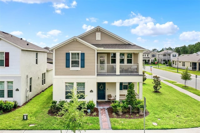 view of front of house featuring covered porch, a balcony, a front yard, and stucco siding