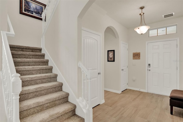 foyer with arched walkways, stairs, and baseboards