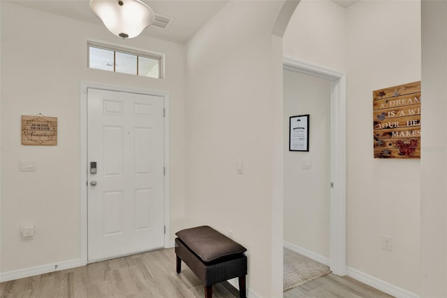 entrance foyer featuring arched walkways, light wood-style floors, and baseboards