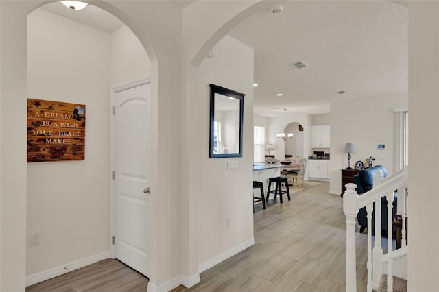 hall featuring a chandelier, baseboards, arched walkways, and recessed lighting