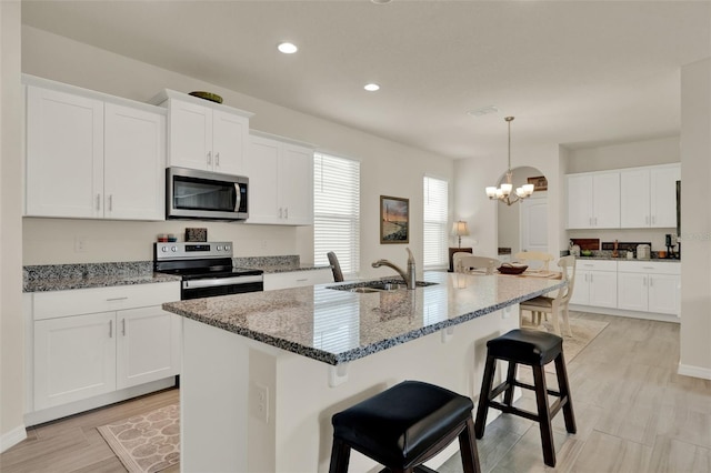 kitchen featuring stainless steel appliances, a sink, a breakfast bar, recessed lighting, and stone counters