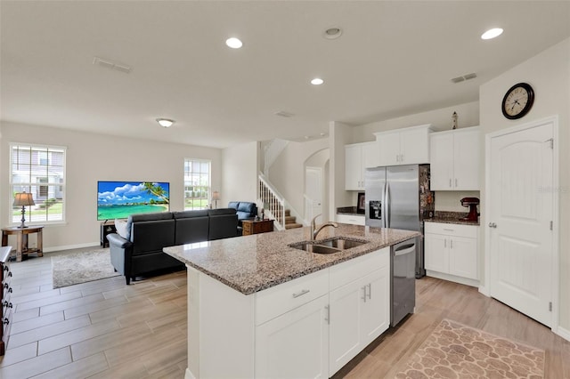 kitchen with a sink, appliances with stainless steel finishes, arched walkways, light stone counters, and wood tiled floors