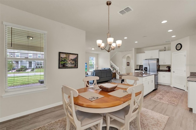 dining room with a chandelier, arched walkways, recessed lighting, baseboards, and light wood finished floors