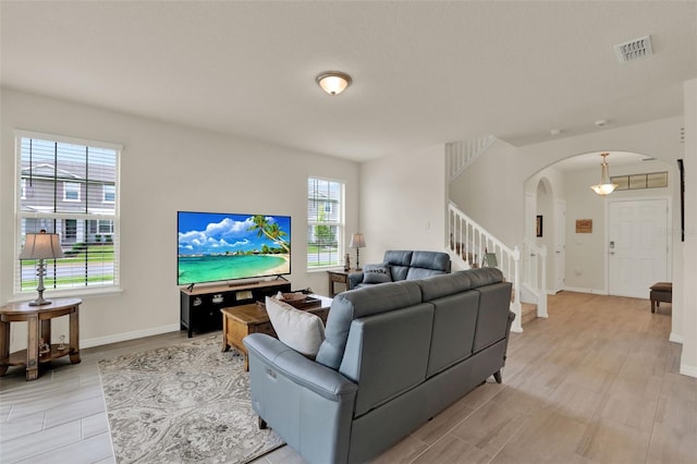 living area with arched walkways, stairs, plenty of natural light, and baseboards