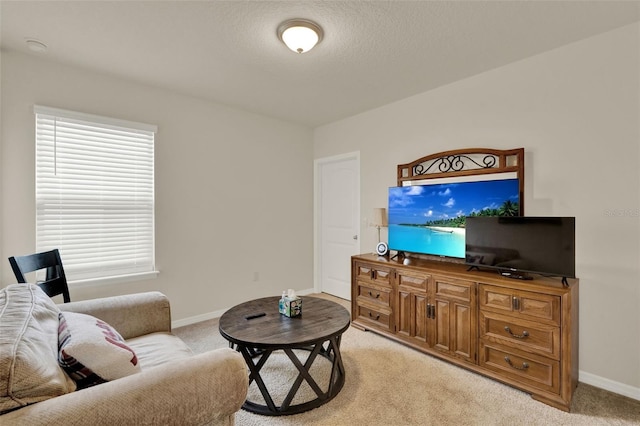 living area with light carpet, baseboards, and a textured ceiling