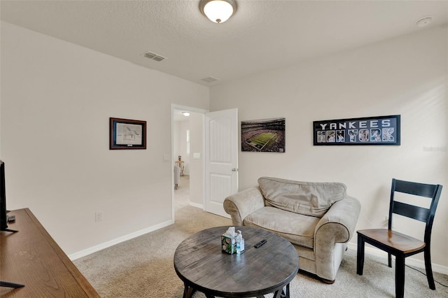 living area with light colored carpet, baseboards, and a textured ceiling