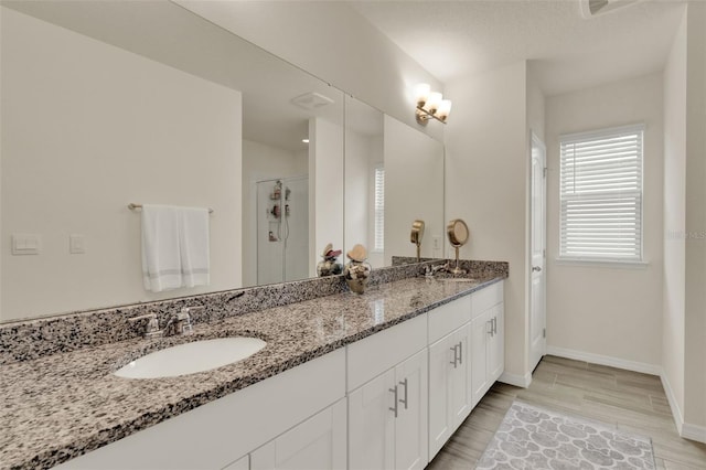 bathroom with double vanity, baseboards, a stall shower, and wood finished floors
