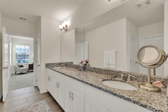 full bathroom featuring connected bathroom, double vanity, wood tiled floors, and baseboards