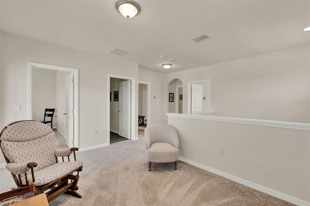 sitting room with carpet floors, baseboards, and arched walkways