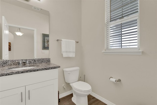 bathroom with toilet, baseboards, vanity, and wood finished floors