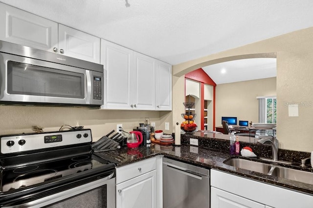 1321 Arbor Vista Loop Unit 301, Lake Mary, FL 32746 - kitchen featuring appliances with stainless steel finishes, arched walkways, white cabinetry, and dark stone counters