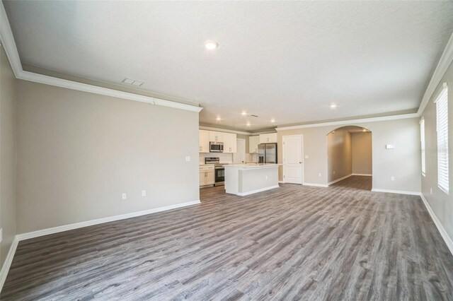 129 Eagleview Loop, Davenport, FL 33837 - unfurnished living room with arched walkways, ornamental molding, wood finished floors, and recessed lighting