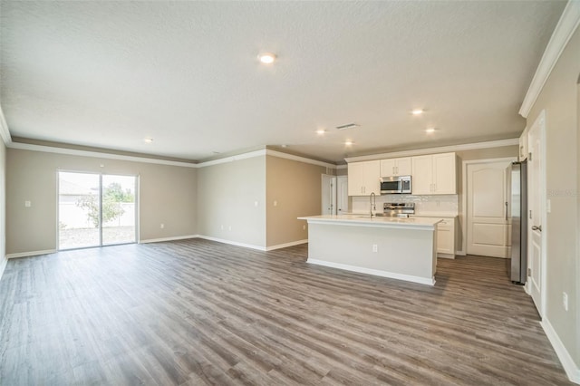 129 Eagleview Loop, Davenport, FL 33837 - kitchen with appliances with stainless steel finishes, ornamental molding, open floor plan, a kitchen island with sink, and dark wood-type flooring