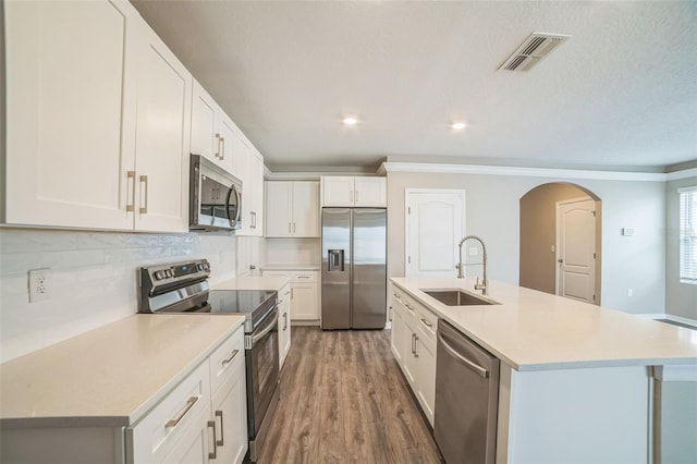 129 Eagleview Loop, Davenport, FL 33837 - kitchen featuring stainless steel appliances, light countertops, arched walkways, wood finished floors, and white cabinetry