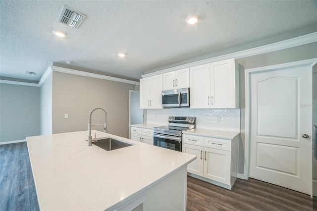 129 Eagleview Loop, Davenport, FL 33837 - kitchen featuring stainless steel appliances, ornamental molding, dark wood-style flooring, white cabinetry, and a kitchen island with sink