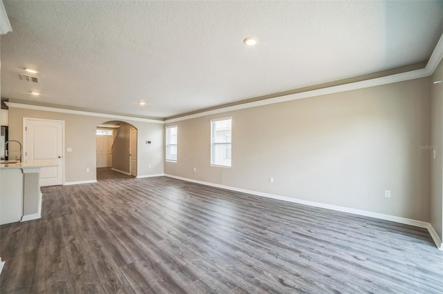 129 Eagleview Loop, Davenport, FL 33837 - unfurnished living room featuring crown molding, arched walkways, dark wood finished floors, a textured ceiling, and recessed lighting