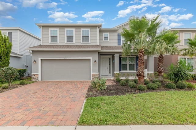 17044 Goldcrest Loop, Clermont, FL 34714 - view of front of house with decorative driveway, stone siding, a garage, a front yard, and roof with shingles
