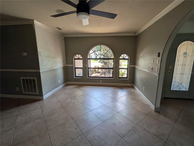 141 Angol St, Punta Gorda, FL 33983 - tiled spare room featuring a textured ceiling, ornamental molding, a textured wall, arched walkways, and baseboards