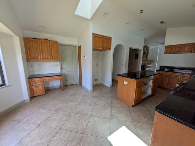 141 Angol St, Punta Gorda, FL 33983 - kitchen featuring a skylight, brown cabinetry, light tile patterned floors, a kitchen island, and dark stone countertops