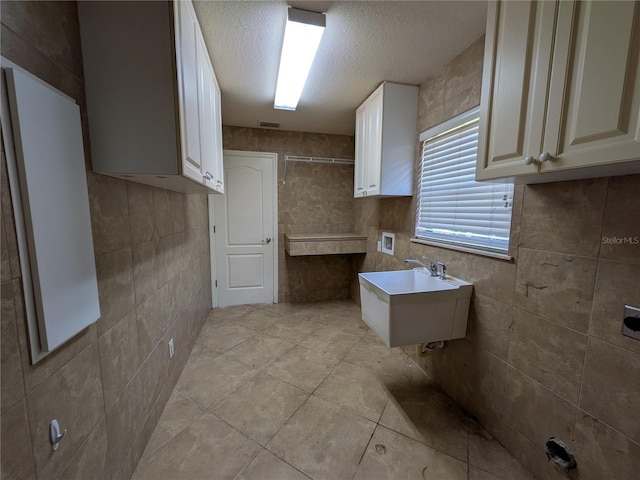 141 Angol St, Punta Gorda, FL 33983 - kitchen featuring a textured ceiling, a sink, light countertops, light tile patterned flooring, and tile walls
