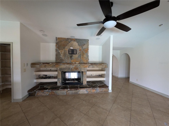 141 Angol St, Punta Gorda, FL 33983 - tiled living room with baseboards, ceiling fan, arched walkways, and a stone fireplace