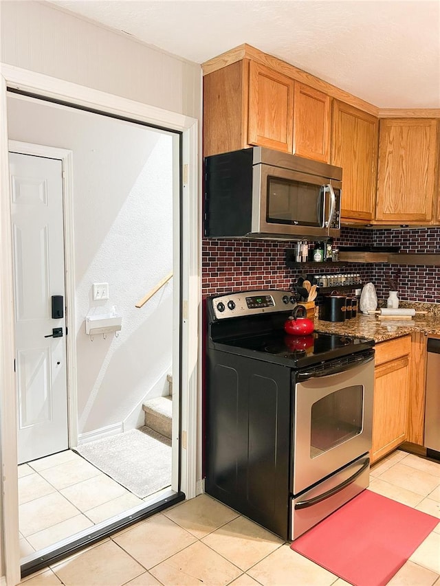 312 W Hull Ave, Oakland, FL 34760 - kitchen featuring stainless steel appliances, tasteful backsplash, light tile patterned flooring, brown cabinetry, and dark stone counters