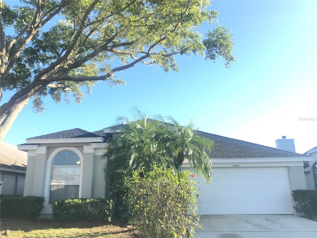 10969 Norcross Cir, Orlando, FL 32825 - view of front of house featuring an attached garage, concrete driveway, stucco siding, and a shingled roof