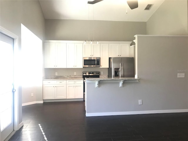 10969 Norcross Cir, Orlando, FL 32825 - kitchen featuring stainless steel appliances, white cabinets, dark wood-type flooring, baseboards, and a kitchen breakfast bar