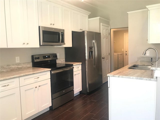 10969 Norcross Cir, Orlando, FL 32825 - kitchen featuring appliances with stainless steel finishes, washer and dryer, a sink, dark wood-type flooring, and white cabinetry