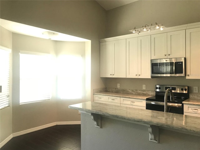 10969 Norcross Cir, Orlando, FL 32825 - kitchen featuring appliances with stainless steel finishes, baseboards, a breakfast bar, and dark wood-type flooring