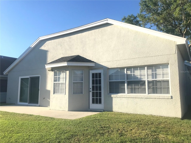 10969 Norcross Cir, Orlando, FL 32825 - rear view of house with stucco siding, a lawn, and a patio