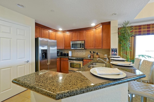 7616 Cabana Ct Unit 301, Reunion, FL 34747 - kitchen featuring appliances with stainless steel finishes, a peninsula, backsplash, light tile patterned floors, and dark stone countertops