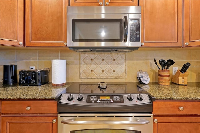 7616 Cabana Ct Unit 301, Reunion, FL 34747 - kitchen featuring stainless steel appliances, decorative backsplash, brown cabinets, and stone countertops