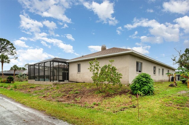 924 Texas St, Englewood, FL 34223 - rear view of house with stucco siding, glass enclosure, a chimney, and a shingled roof