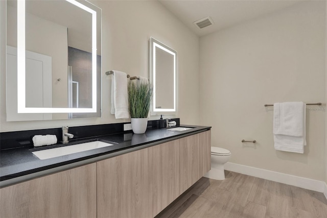 17441 Hidden Forest Dr, Clermont, FL 34714 - bathroom with double vanity, toilet, wood finished floors, and baseboards