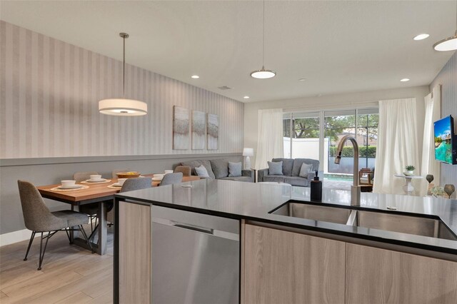 17441 Hidden Forest Dr, Clermont, FL 34714 - kitchen featuring stainless steel dishwasher, wallpapered walls, light wood finished floors, a sink, and hanging light fixtures