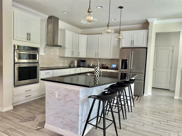 14117 Larkspur Lake Dr, Winter Garden, FL 34787 - kitchen featuring appliances with stainless steel finishes, wall chimney exhaust hood, a sink, light wood-style flooring, and a breakfast bar area