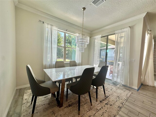 14117 Larkspur Lake Dr, Winter Garden, FL 34787 - dining room featuring a chandelier, a textured ceiling, baseboards, light wood-type flooring, and ornamental molding